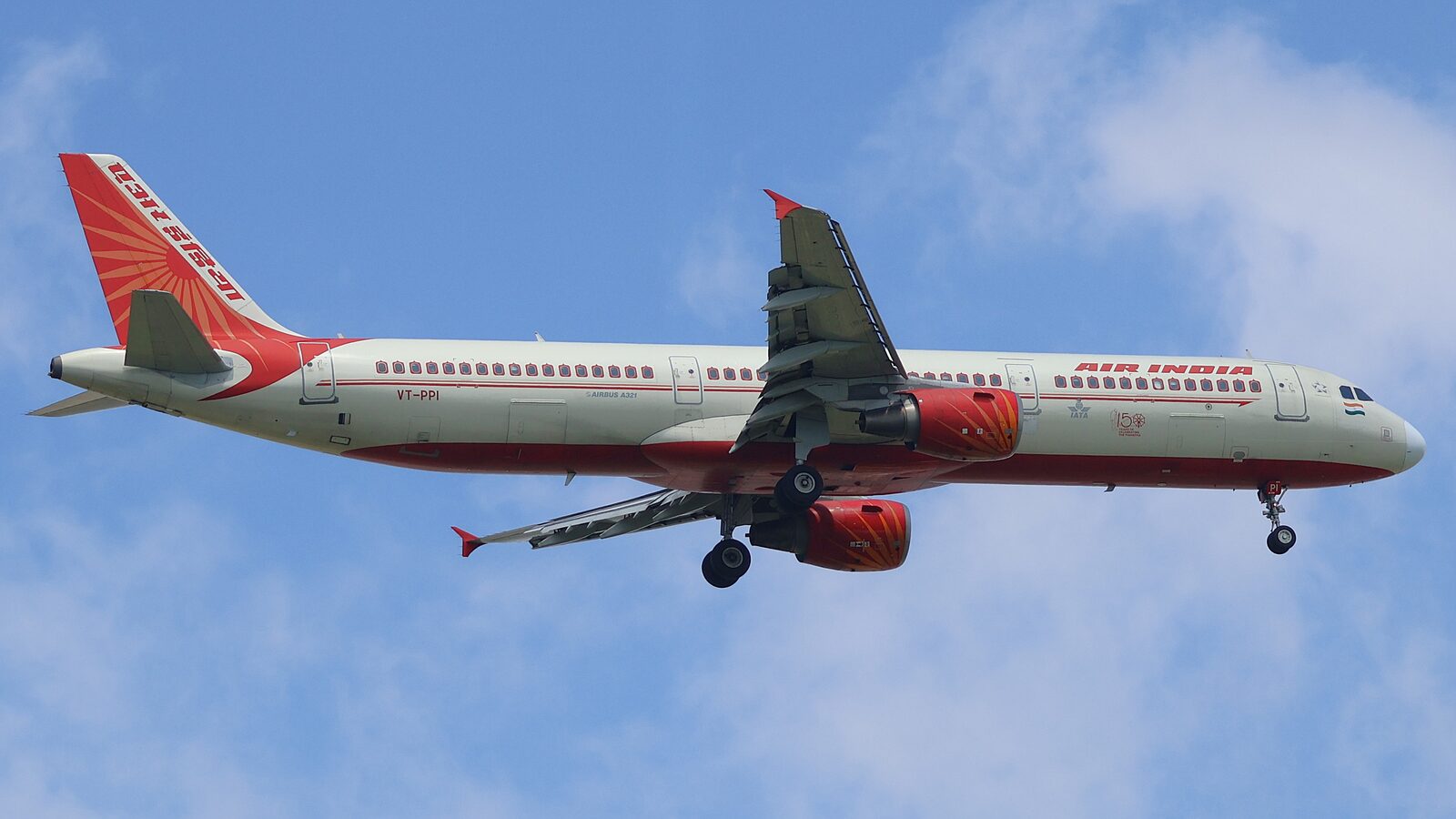 Air India Airbus A321 in red and white livery on approach to Singapore Changi Airport against a blue sky