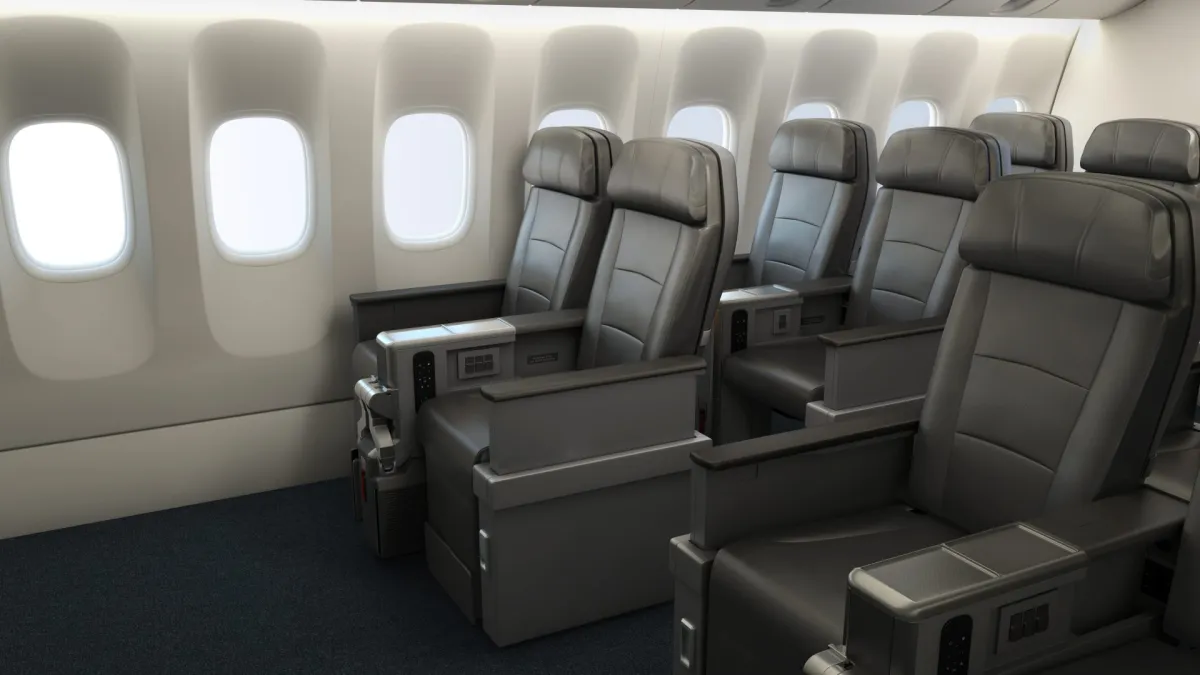Two rows of American Airlines Premium Economy seats, wide grey leather recliners beside large cabin windows in a bright empty cabin