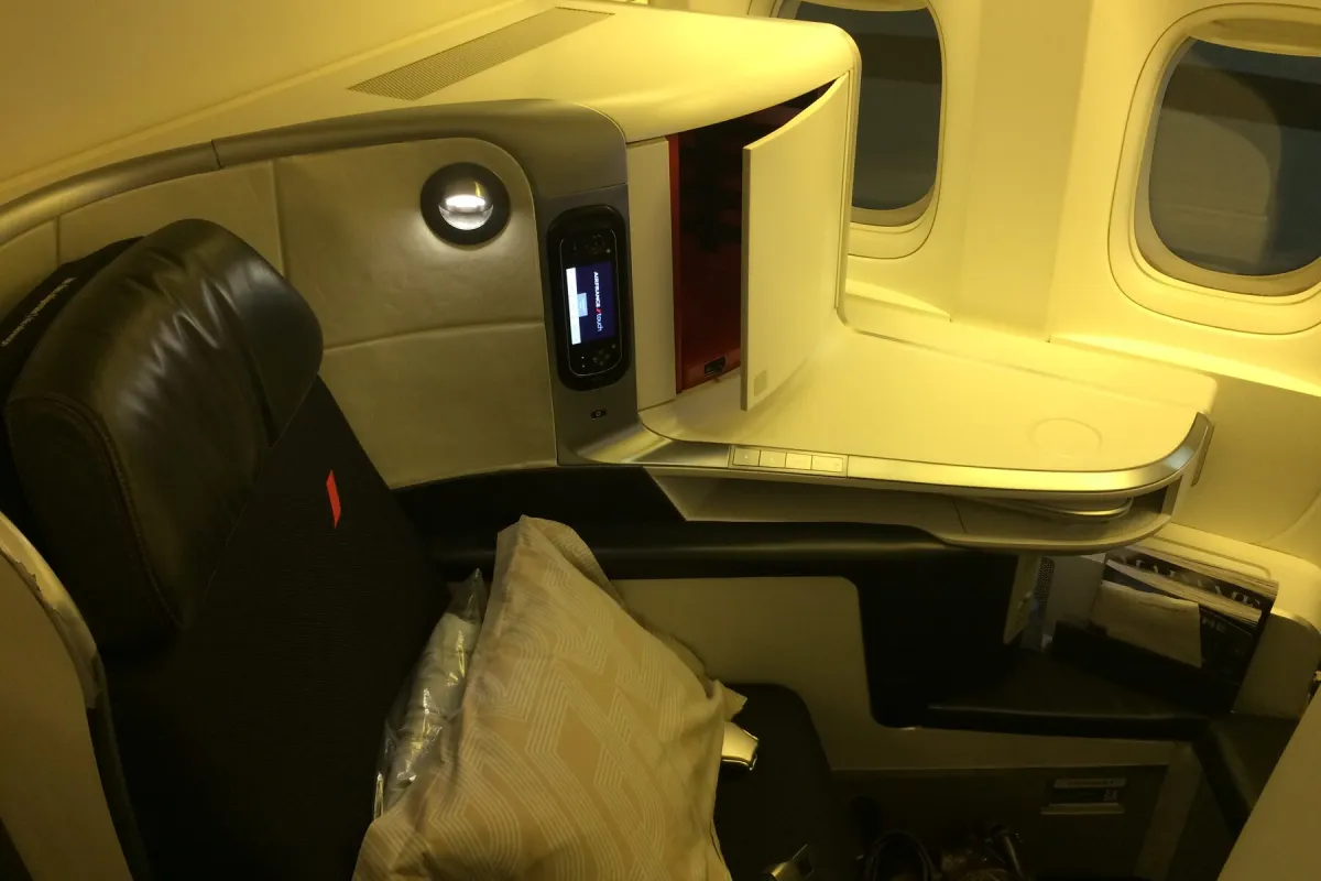 A premium business-class seat with warm cabin lighting.